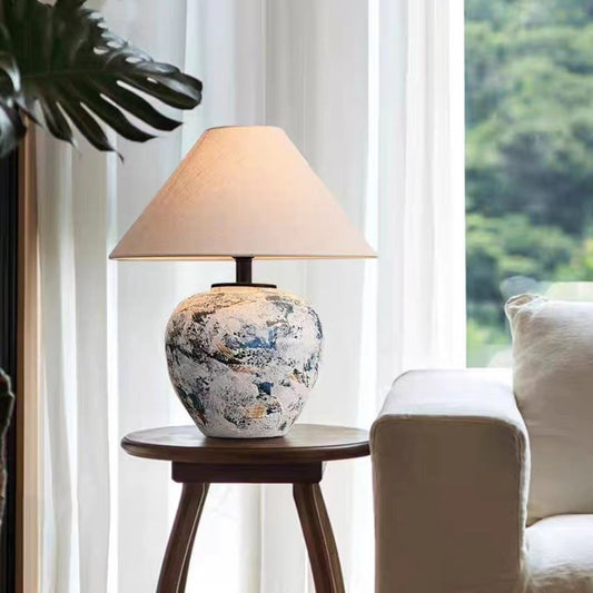 Handmade ceramic table lamp in indigo tones styled beside living room armchair